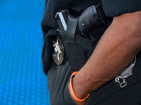 An armed patrolman stands on a platform in a North American transit station.